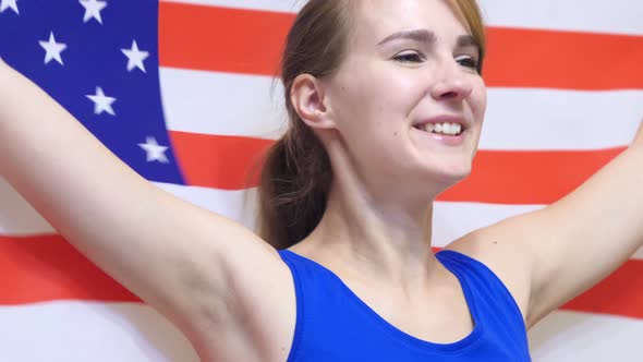 American Young Woman Celebrates while Holding the Flag of USA alt