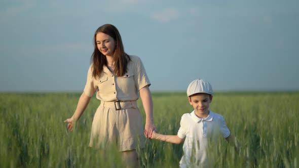 Mom and Sevenyearold Son Walk Through a Wheat Field on a Sunny Summer Day