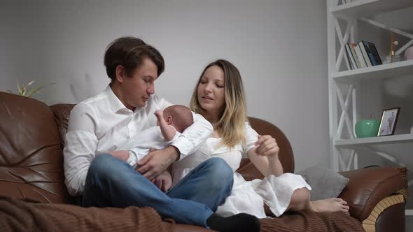 Wide Shot Portrait of Happy Couple of Parents Sitting with Newborn Baby Son on Comfortable Couch in alt
