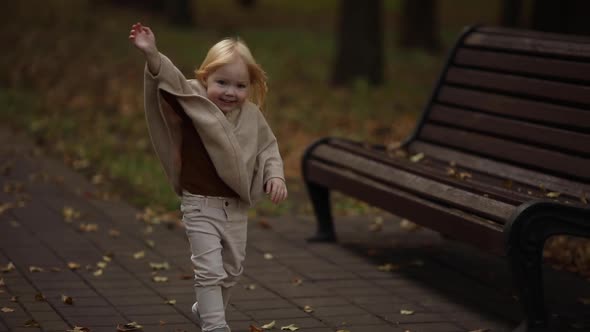 Happy Cute Baby Girl Running Around the Autumn Park