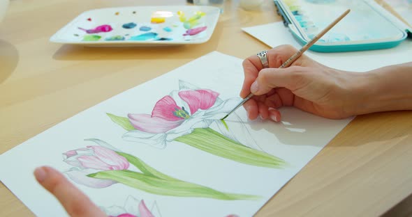 The Artist Paints Flowers. Watercolor Drawing. Hand Drawing with a Brush. Female Hand with a Brush alt