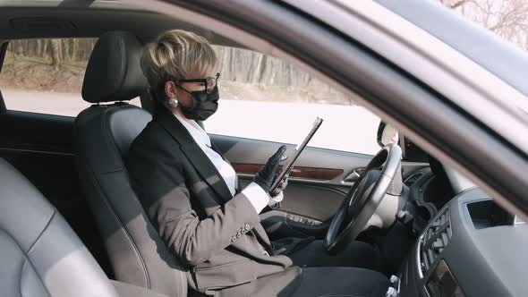 A Businesswoman in Glasses Is Working in a Car alt