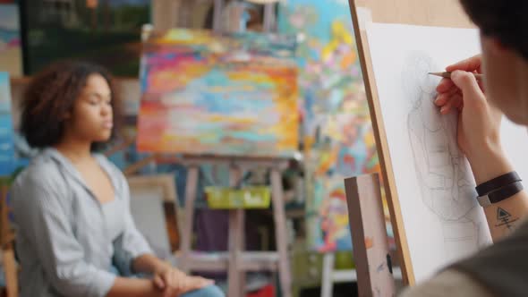 Close-up of Female Hand Drawing Portrait of Afro-American Woman Model in Arts Class alt