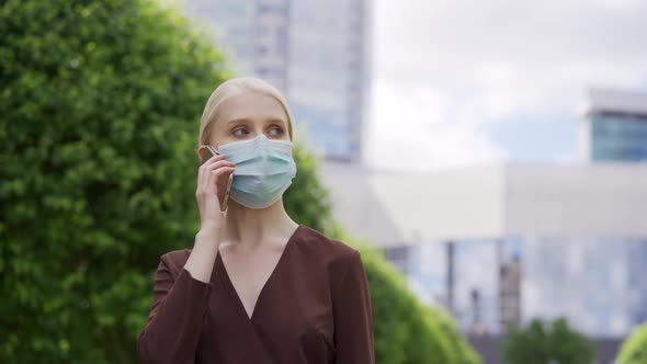 Business Woman in a Medical Mask with a Phone in Her Hands on the Street