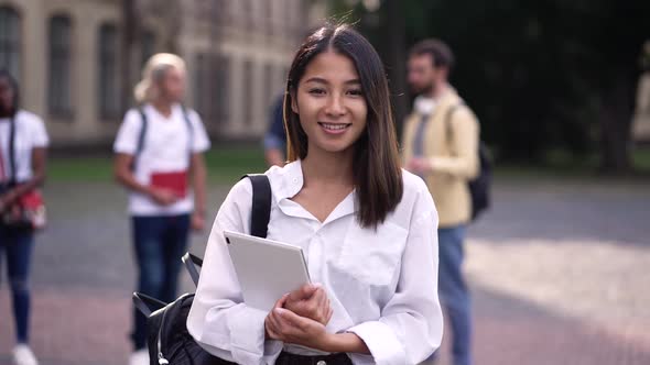 Smiling Asian Girl Student Posing in Campus Park alt