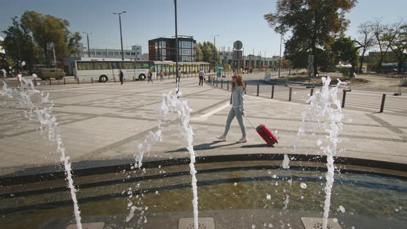 A Young Woman is Walking Through the Square Near the Train Station alt