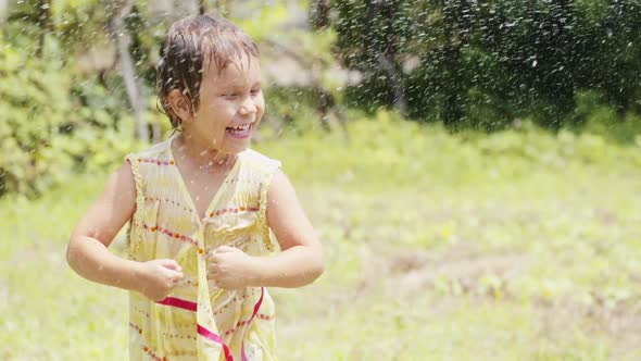 Little Girl Dancing Under the Spray From a Garden Hose alt