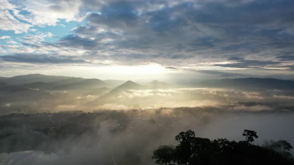 Landscape view of the city of rural village in valley on foggy day while the sun is raising by drone