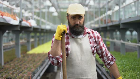 Tired Worker Looking Seriously at Camera in Greenhouse Exhausted by Low-Paid Job