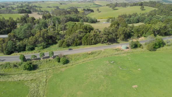 A car parked on a country road in the green hills of the Strzelecki ranges Australia. alt