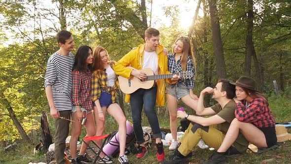 Young Funny Guy Performing His Song To a Friends While Resting Outdoors alt