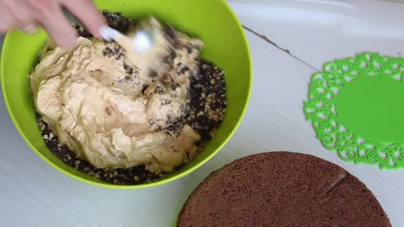A Woman Mixes Peanuts And Chocolate In A Container. alt