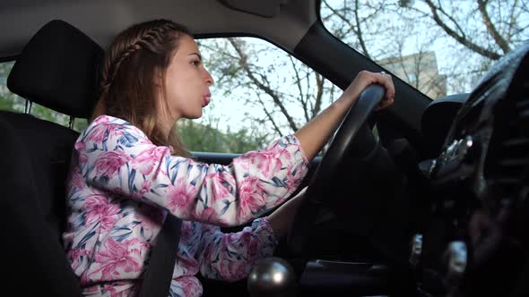A Woman Driving in a Good Mood Inflates Chewing Gum alt