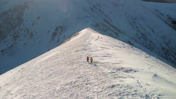 Mountaineers Walking on Snowy Mountain Ridge