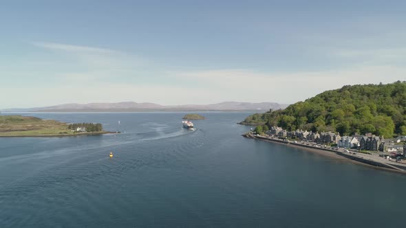 Aerial shot revealing the sea entrance to Oban with Ferry departing towards Mull alt