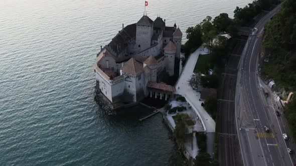 Aerial shows Chillon castle from above and tilting up to Lausanne city, Switzerland alt