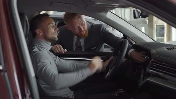 Man Discussing Car with Salesman in Auto Dealership Showroom alt