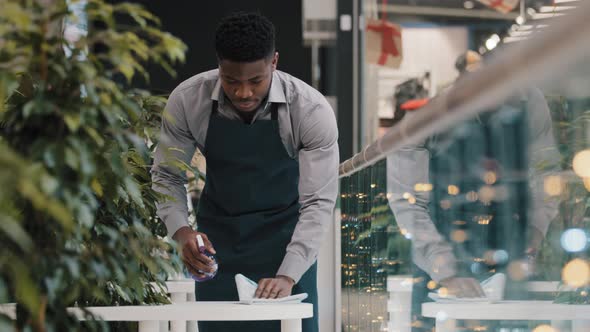 Young Man Waiter in Apron Does Cleaning Restaurant Wipes Table Wiping Off Dirt Treated with alt