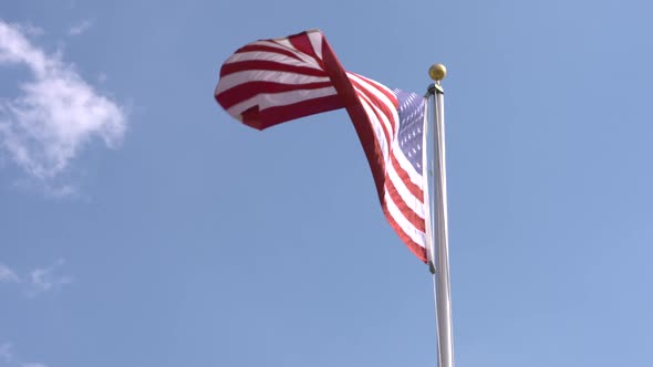 American flag waves proudly against a blue sky background. Shot in slow motion alt