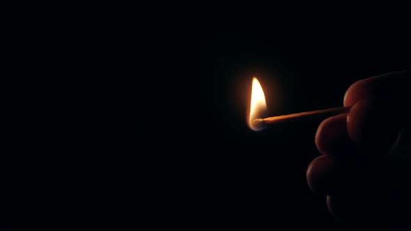 Slow Motion Burning Match in Hands in Darkness