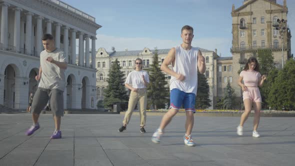 Group of Professional Dancers Performing on City Square at Sunrise. Four Confident Caucasian Men and alt