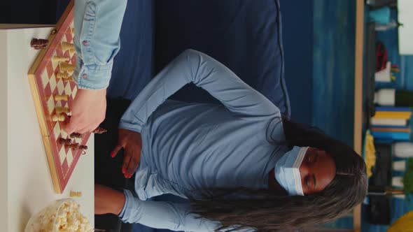 Vertical Video African Woman Wearing Face Mask Playing Chess with Man alt