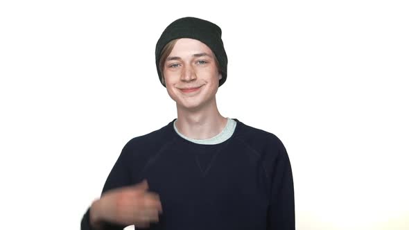 in Slow Motion Portrait of Positive Caucasian Hipster Teenager Wearing Hat Smiling Showing Thumb Up alt