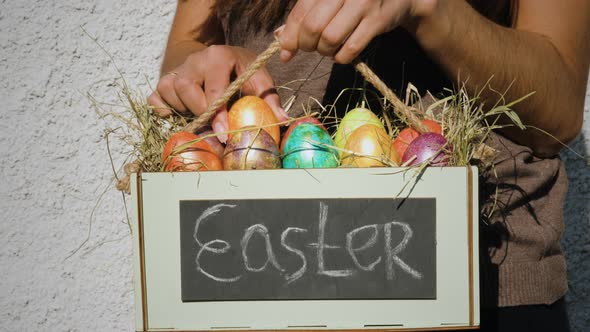 Woman put colored easter egg into a box alt