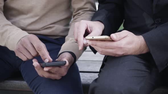 Businessman with Smartphones Showing Colleague Online App alt