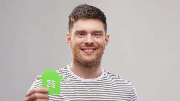 Smiling Young Man Holding Green House Icon alt