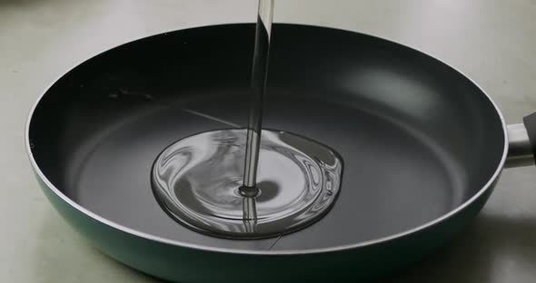 Slow motion: close-up of pouring oil into a frying pan for cooking