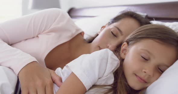 Mother and daughter sleeping on bed in bedroom at home 4k alt