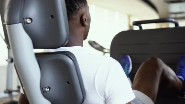Back View of African American Man Doing Exercise on Leg Press During Fitness Training in Modern Gym alt