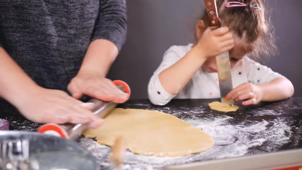 Mother and daughter baking sugar skull cookies for Dia de los Muertos holiday. alt