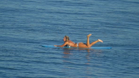 A young woman surfing in a bikini on a longboard surfboard. alt