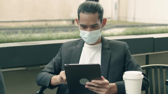 Asian businessman using a tablet checking email while sitting in the coffee shop.