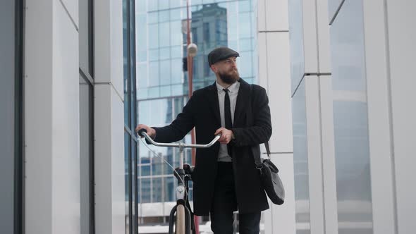 A Handsome Man in a Suit Walking Holding a Bicycle Near Business Center