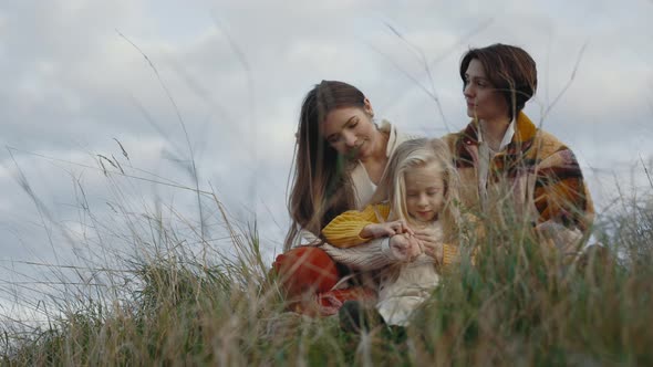 Two Loving Women Playing with Daughter on Nature alt