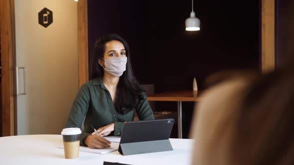 Two Businesswomen Wearing Masks Having Socially Distanced Meeting In Office During Health Pandemic