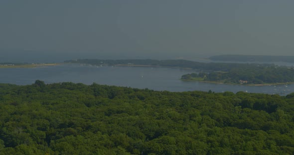 Aerial Pan of Dense Forest Trees and Bay Seen from a Distance in Long Island alt