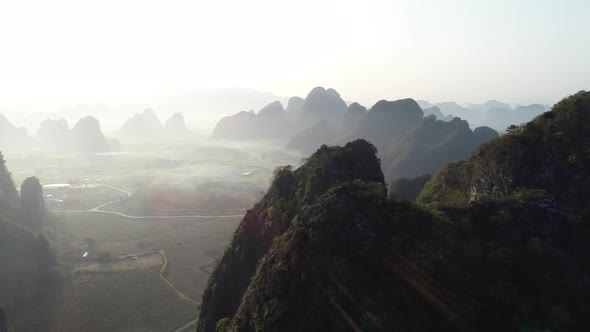 Aerial footage of beautiful sunrise over foggy karst mountain peak landscape alt