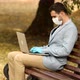 Young businessman with face mask working outdoors on bench in city, using laptop. - VideoHive Item for Sale