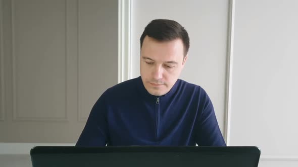 Calm business man checks his email, suddenly receiving great news on his laptop