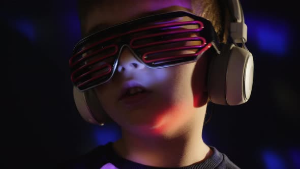 A Little Boy in Headphones Listens To Music, Sings