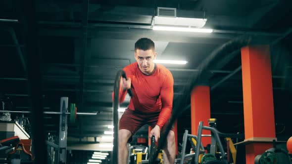 Athlete Is Having a Workout with Ropes in the Gym alt