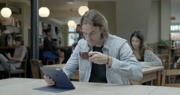 Man using tablet and drinking coffee in pub