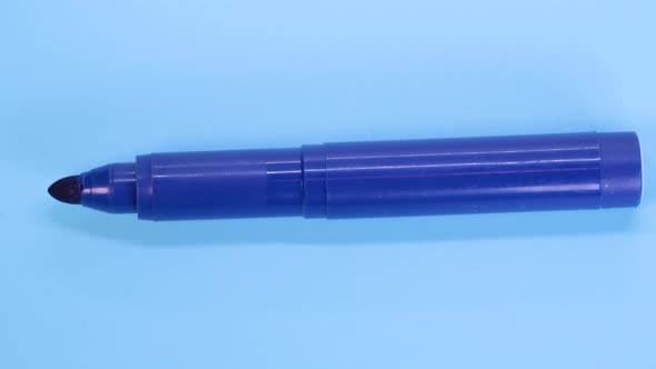 Blue marker pen rotating on blue surface background, macro shot close up view detail. alt