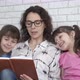 Mother reads a book to children.