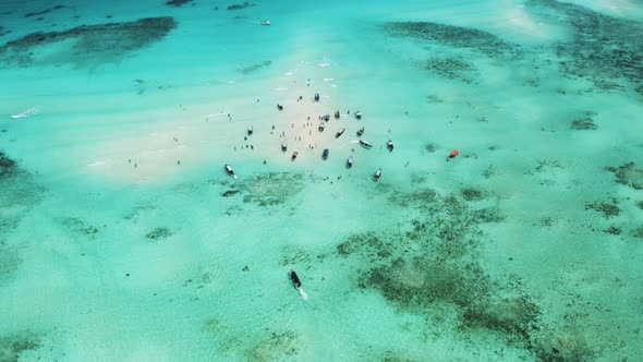 Motor boats sailing to shallow tropical sandbank anchorage with people. alt