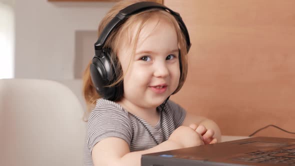 Child Listens to Music in Headphones Dances Rejoices and Smiles